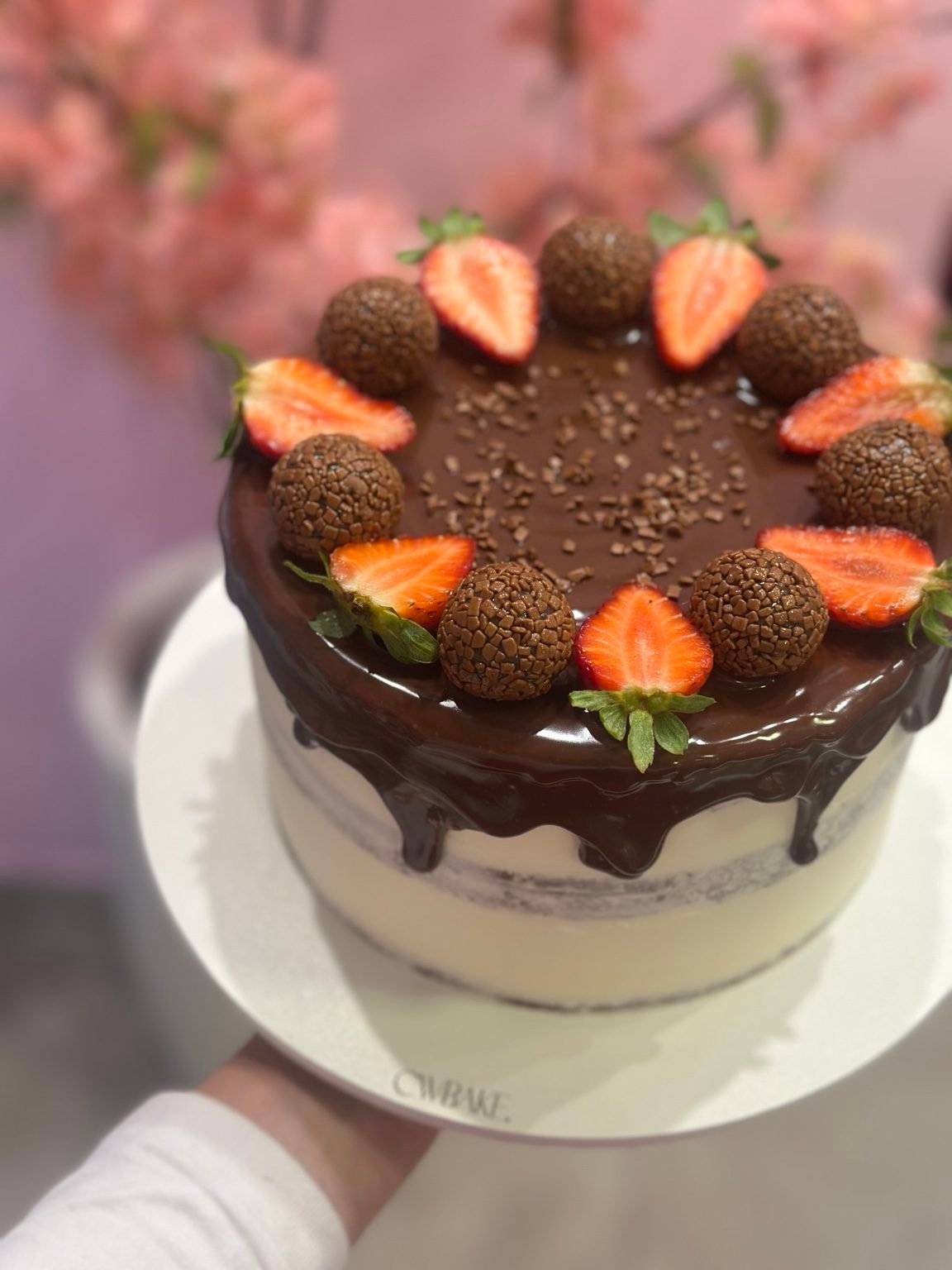Bolo com cobertura de chocolate, morangos frescos e brigadeiros no topo