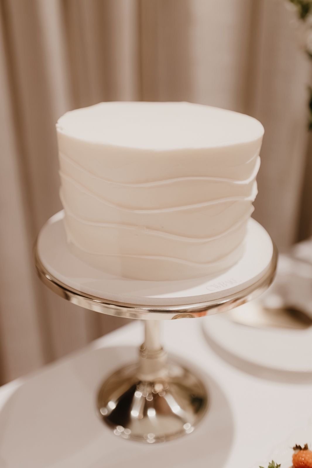 Bolo branco com textura em ondas, sobre suporte de metal