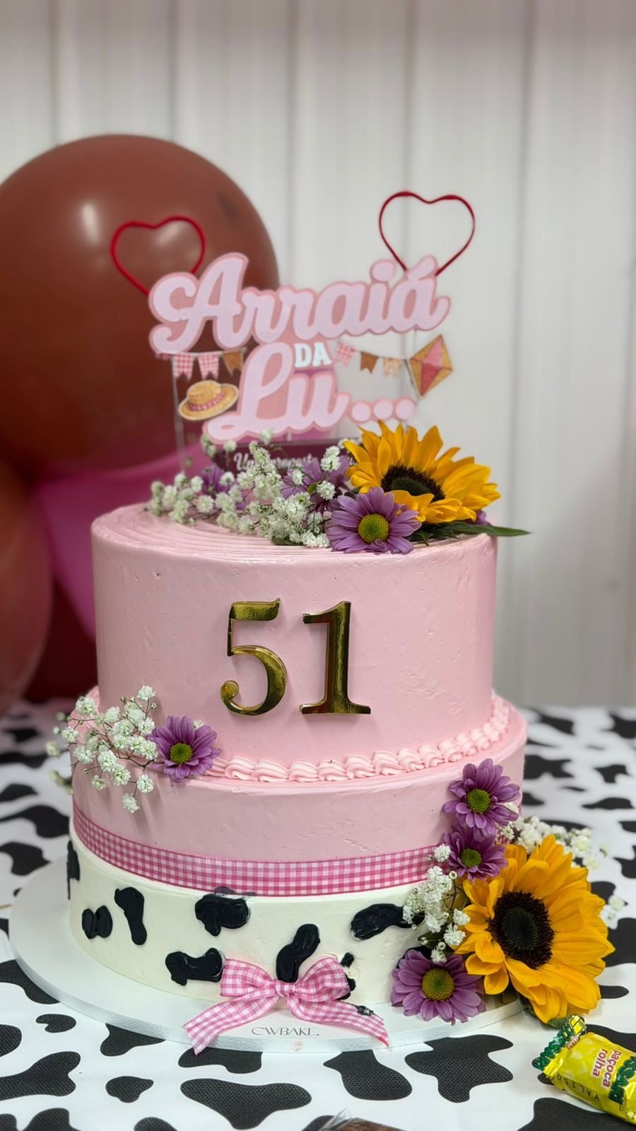 Bolo cor-de-rosa de dois andares com tema de festa junina, girassóis e o número 51