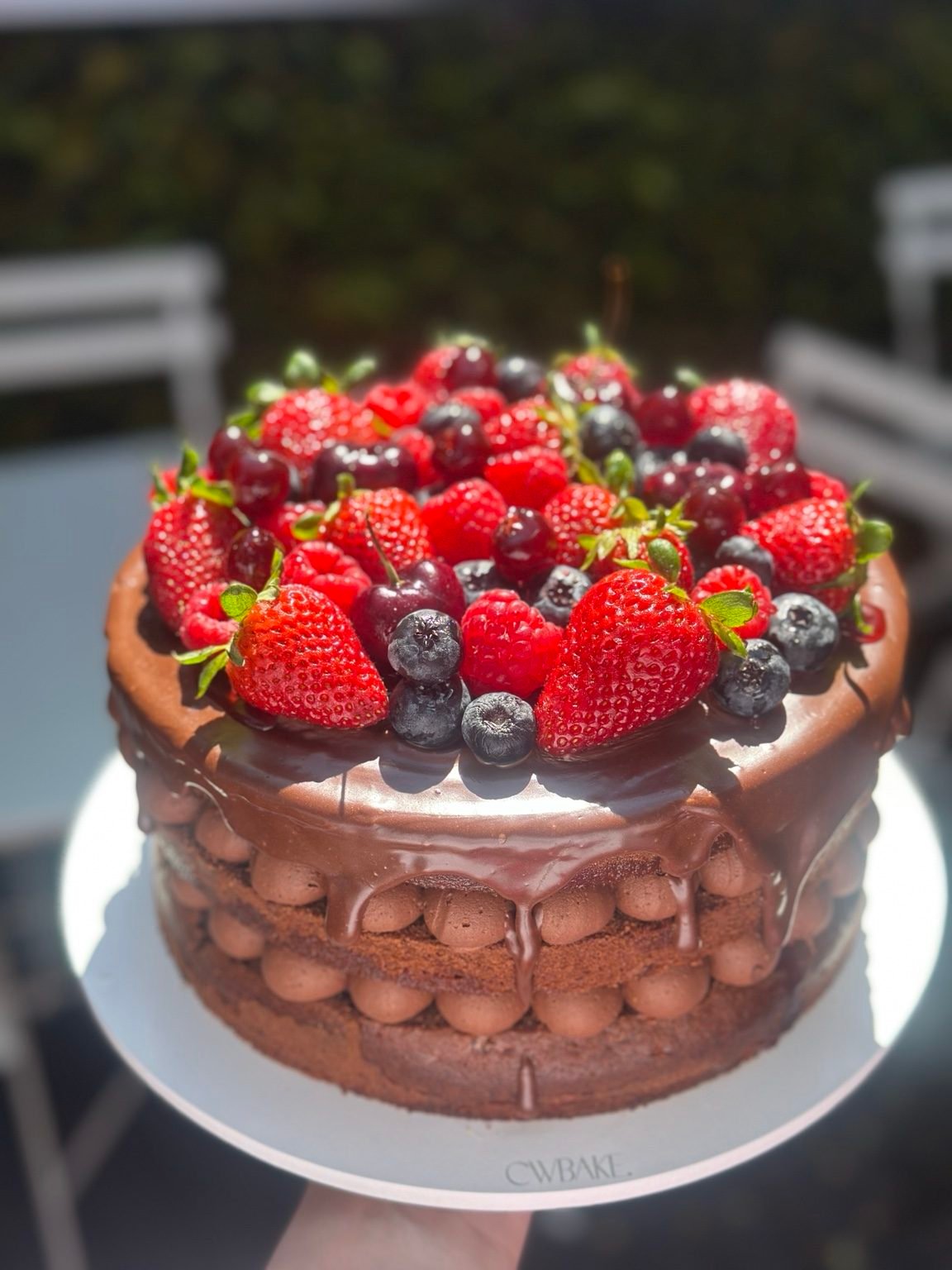 Bolo de chocolate com morangos, mirtilos e frutas vermelhas no topo
