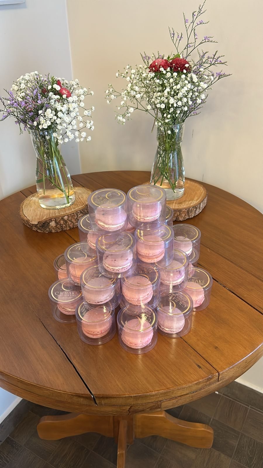 Mesa com potinhos de presente com macarons e vasos de flores