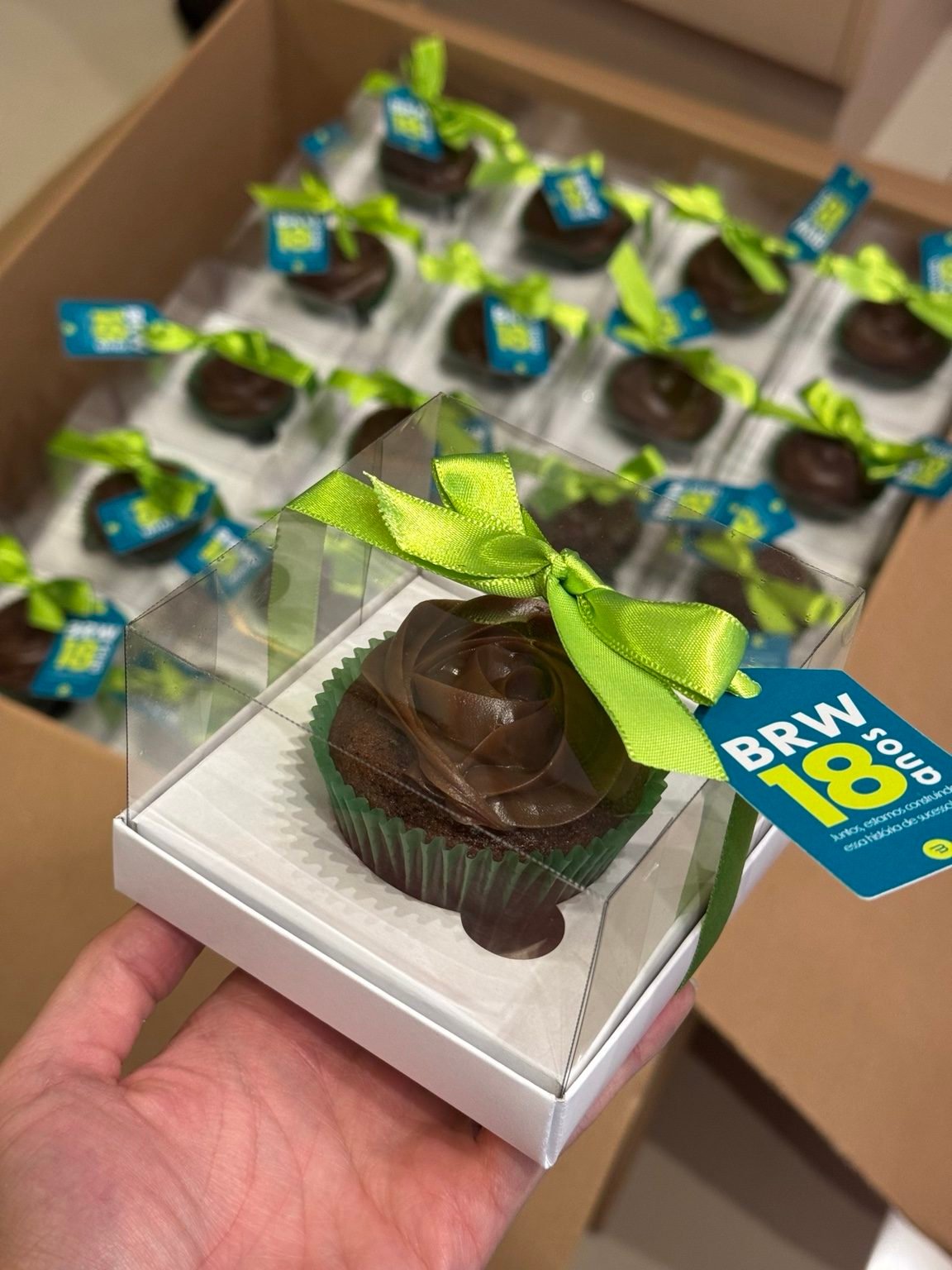 Cupcake de chocolate em caixinha individual com laço verde e etiqueta personalizada
