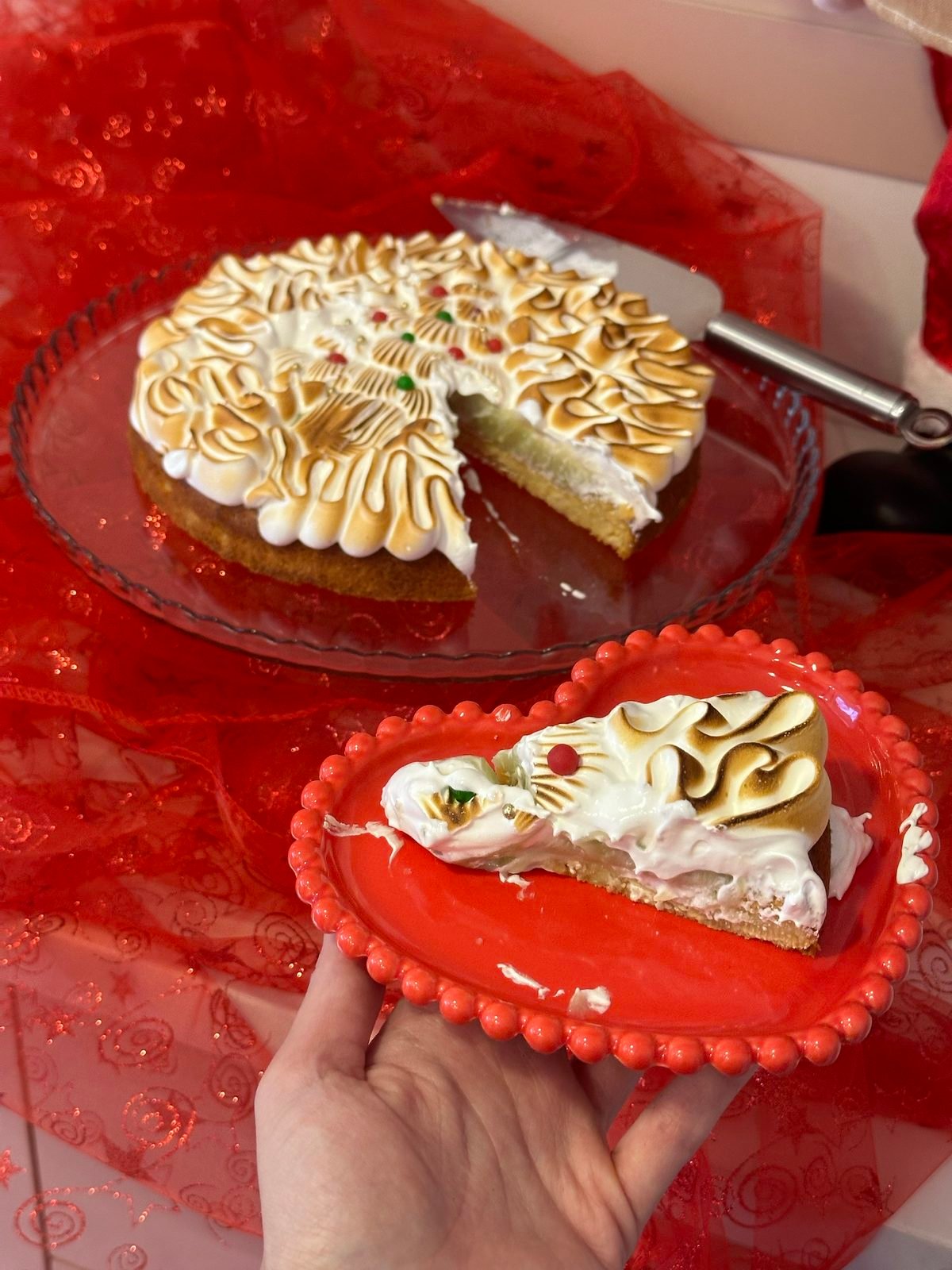 Torta coberta de merengue maçaricado em picos, com uma fatia servida ao lado